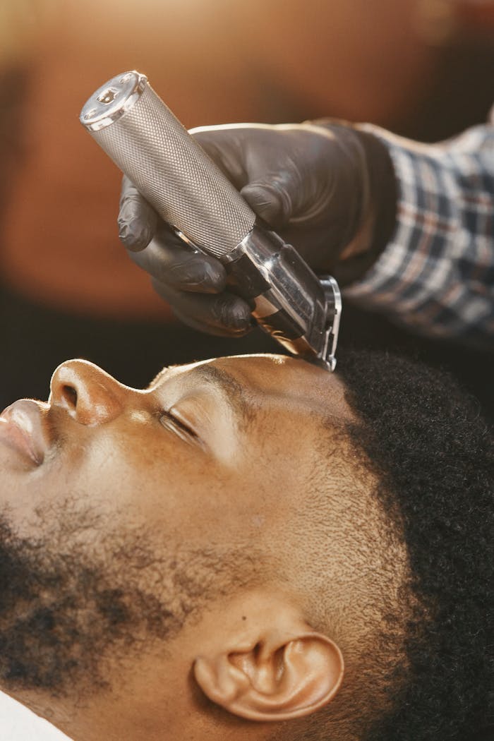African American man receives a precise haircut with a hair clipper. Close-up view.
